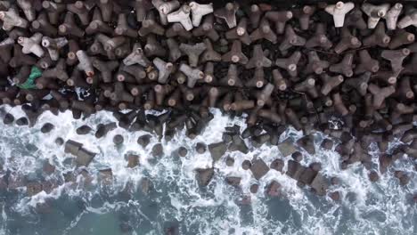 aerial view of sea wave crashing tetra concrete block or wave breaker stone at glagah beach, indonesia