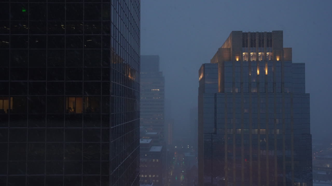 Static establishing shot of tall building in a city during snow storm