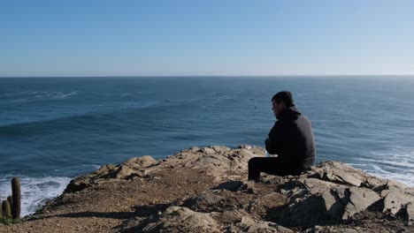 hombre quitándose su mascarilla viaje pandémico nueva forma de viajar el hombre mira desde un punto de vista en punta de lobos surf point en chile con mascarilla en la nueva normalidad de chile cactus saludable libre de covid