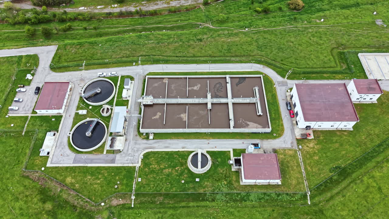 Water treatment facility operating in a rural area with multiple tanks and buildings during daylight hours