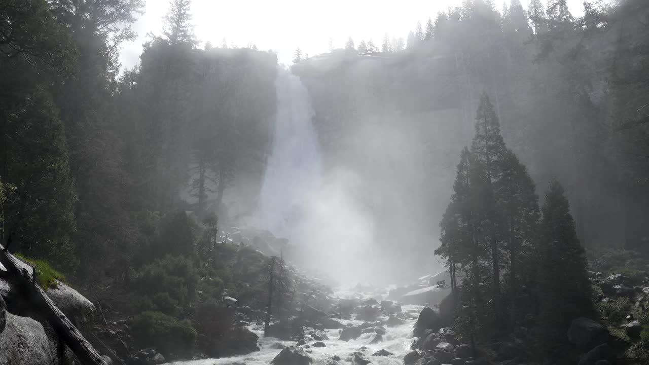 Cascada majestuosa con niebla ascendente en un bosque rocoso