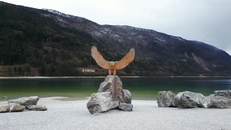 wooden eagle sculpture on the rock in molveno lake in trentino, italy