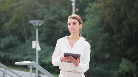 Young-attractive-businesswoman-walks-up-the-stairs-with-a-tablet-in-her-hand