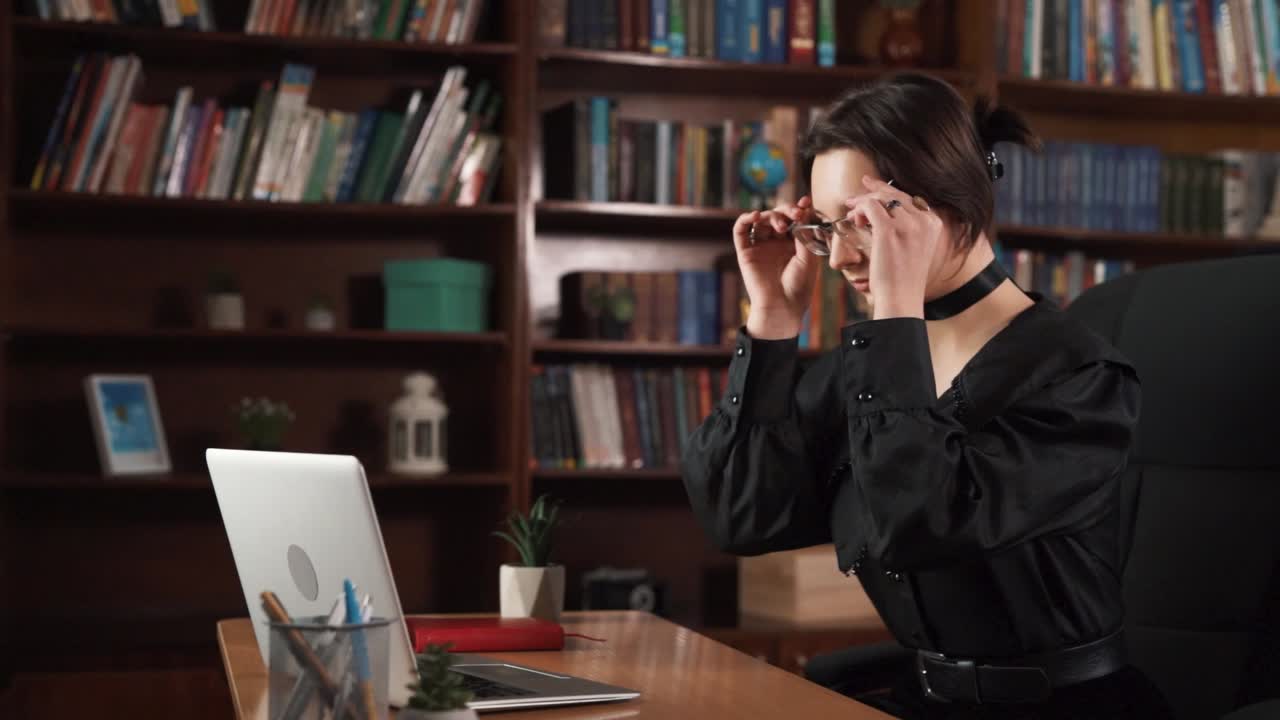 소녀는 그녀의 앞에 노트북과 함께 의자에 앉아 있습니다