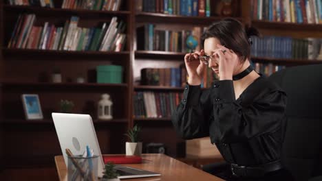 la chica está sentada en una silla con una computadora portátil frente a ella
