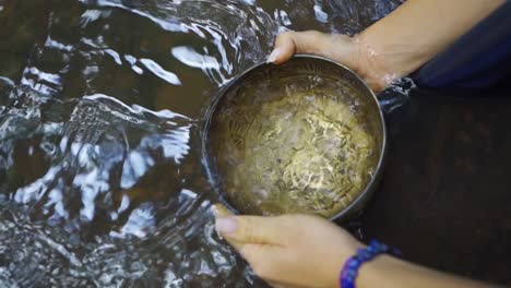 Nahaufnahme-Von-Frauenhänden,-Die-Einen-Topf-In-Sauberes-Wasser-Tauchen-Und-Wasser-Sammeln