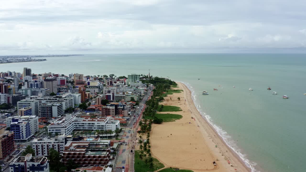 Rotating aerial drone wide shot of a large round building on the beach in the colorful tropical beach capital city of Joao Pessoa in Paraiba, Brazil from the Tambaú neighborhood on an overcast morning