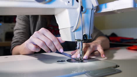 process of sewing fabric on a sewing machine. tailor working with sewing machine at workshop. female's hand pushing material through sewing machine.