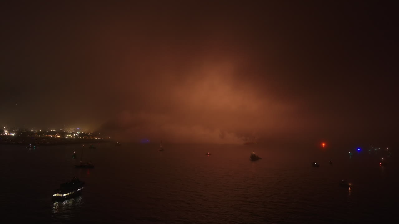 7월 4일 바다 위의 흐린 안개 속에서 공중에서 불꽃놀이가 확산되고 있습니다.