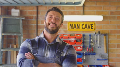 portrait of smiling man wearing overalls in garage workshop at home