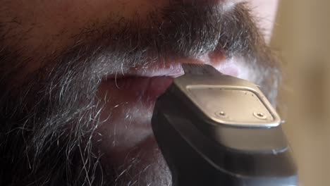 man trimming mustache with electric shaver