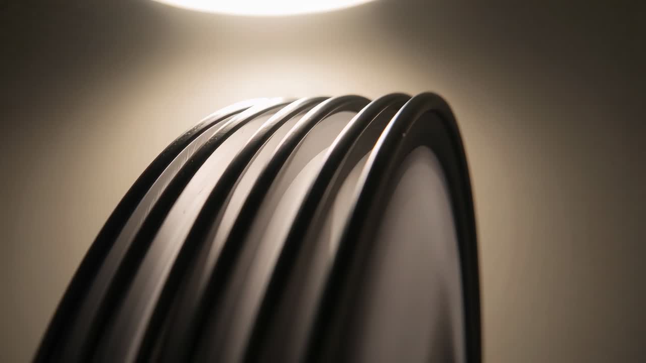 Revealing cluster of curved dark rods shifting under overhead circular lamp, showing rim detail