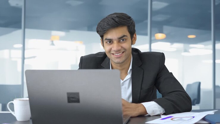 Happy Indian working in an office and smiles towards camera