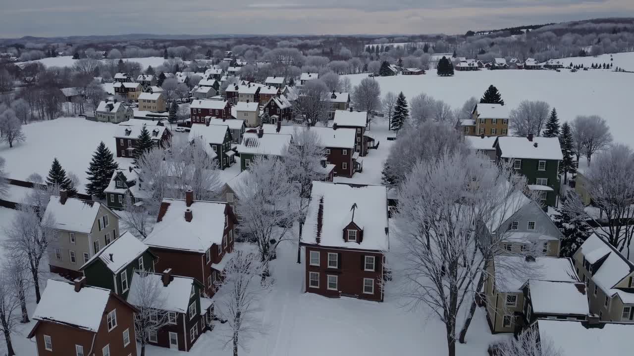 Aerial view of a picturesque winter village blanketed in snow, showcasing charming houses and frosted trees, capturing the serene beauty of a snowy landscape