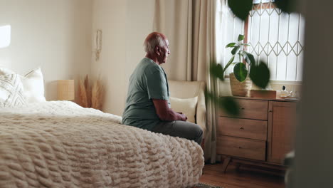 elderly man sitting in bedroom, looking out the window