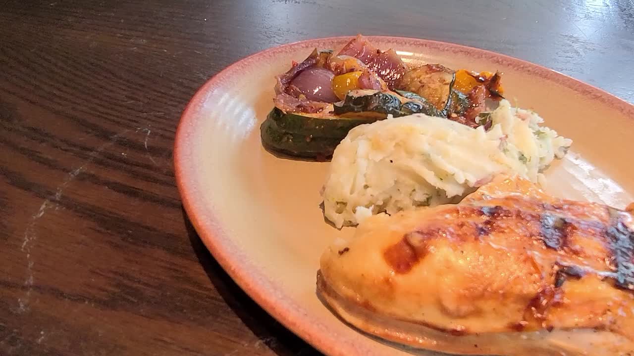 1-2 dolly dangle cámara en semicírculo sobre delicioso pollo asado a la parrilla con verduras a la parrilla y puré de patatas con ajo sazonado servido en un plato de cerámica sobre una mesa vintage de madera