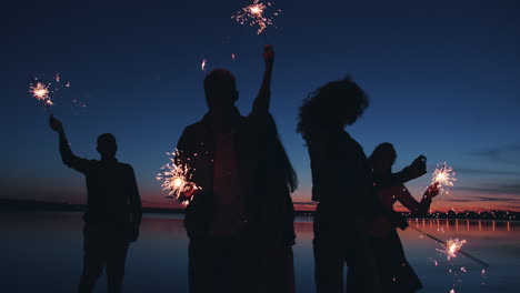 friends celebrating with sparkler at sunset lake