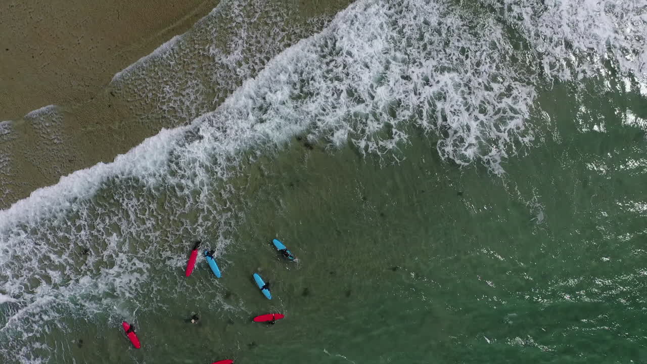 antena vertical: los surfistas aprenden sobre olas pequeñas, tablas de surf rojas y azules