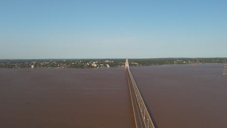 aerial orbit shot of santa cruz bridge over rio parana river during sunny day with blue sky