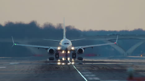 passenger jet takes off from runway just before dark with headlights prominent