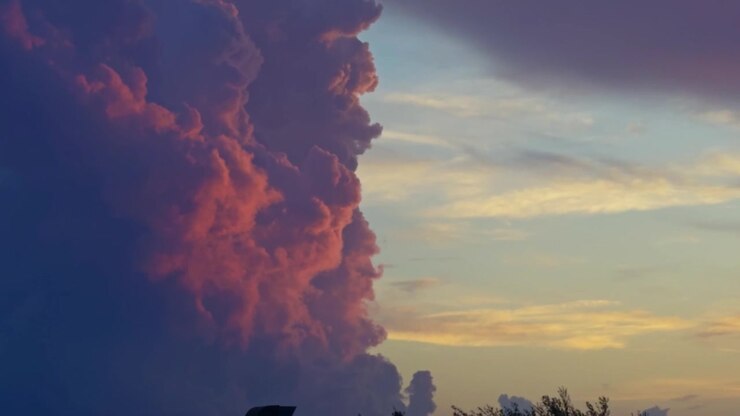 Majestic pink and purple cumulonimbus clouds forming in the sky during a dramatic and colorful sunset. Breathtaking and awe-inspiring view
