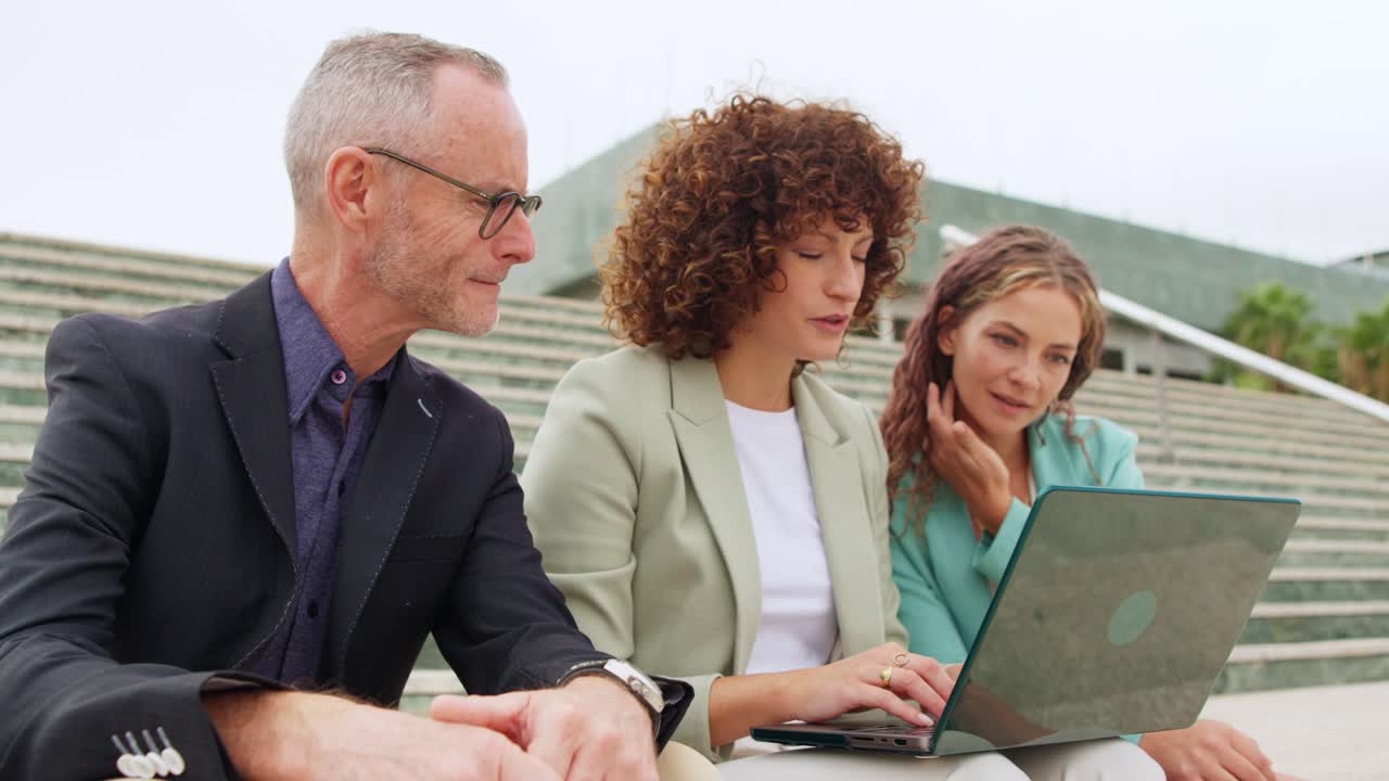 Equipe de negócios colaborando ao ar livre com um laptop