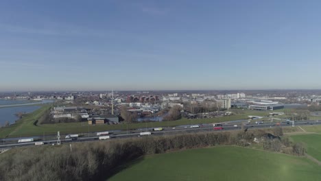 Drone-shot-of-a-city-and-highway-behind-grass-fields