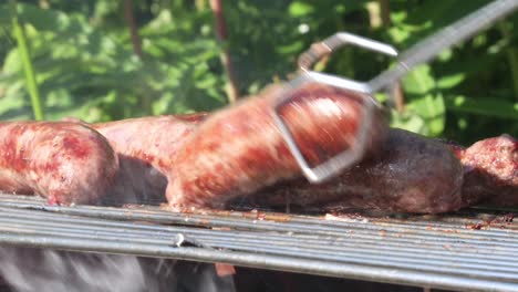 Tongs-turning-sausages-on-barbecue