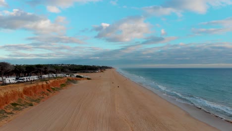 Beach-with-pines,-cliffs-and-caravans-at-the-end-of-a-cloudy-day