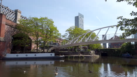 Statischer-Schuss-Von-Kanadagänsen-Auf-Dem-Kanal-In-Manchester-Mit-Stadtbild-Im-Hintergrund-An-Einem-Sonnigen-Tag