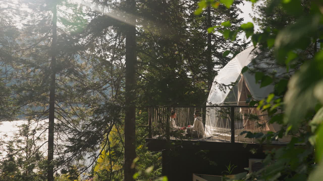 Exclusive glamping haven for yoga practice. Husband and wife spend time together meditating near semi-spherical dwellings. Immersive natural environment