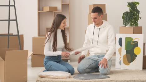 young couple moving into new house sitting on floor and assembling coffee table together 1