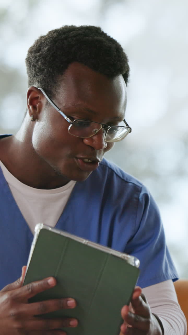 Giovane uomo afroamericano in camice che usa un tablet e parla
