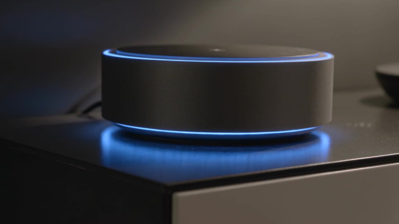 Cavo di alimentazione che eroga corrente, con l'anello LED blu pulsante di un gadget cilindrico compatto su una console multimediale.