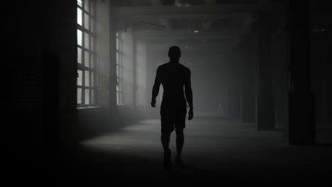 Mannsilhouette-Geht-Im-Dunklen-Korridor.-Sportler-Macht-Nach-Dem-Training-Eine-Pause