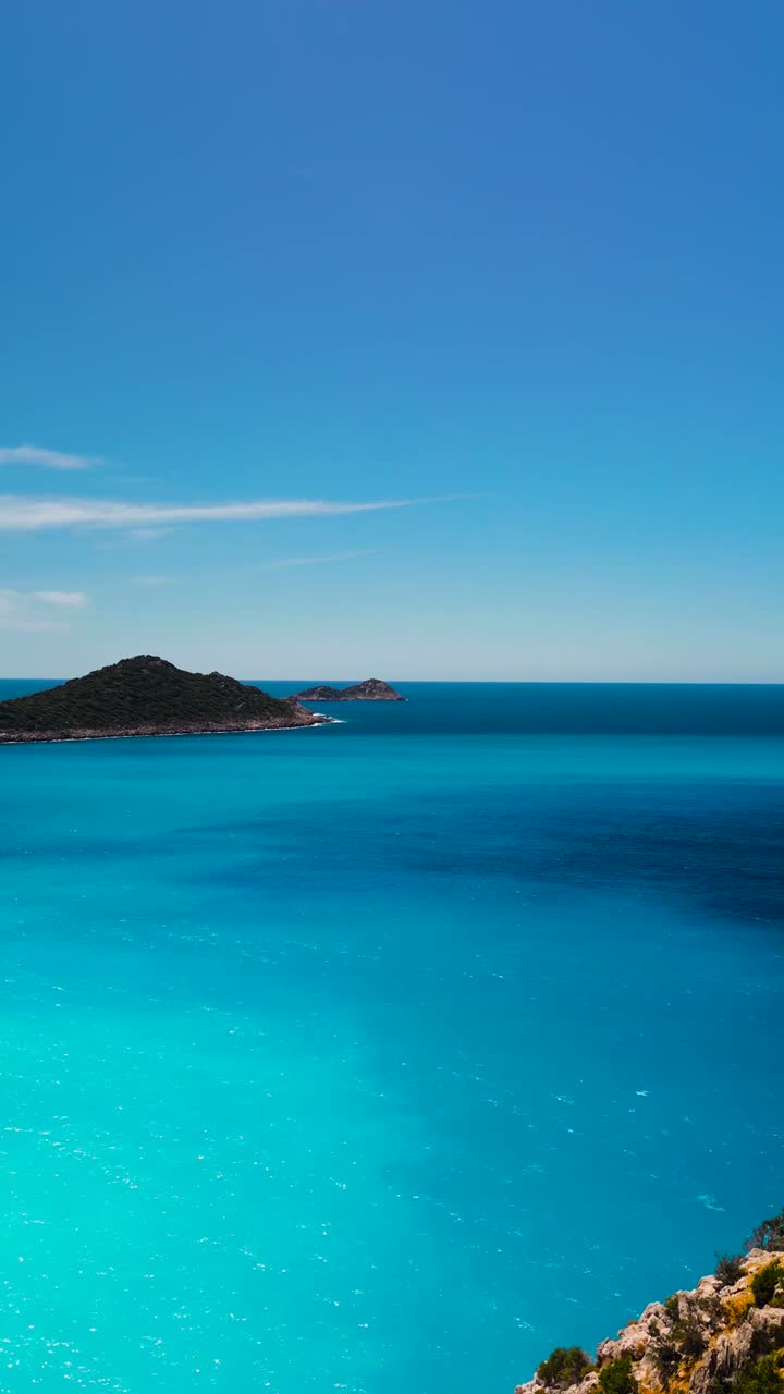 Aerial drone view showing cliffside coastal road curving above turquoise sea near Kas peninsula with scenic islands, perfect for Social Media travel content and summer landscape scenes