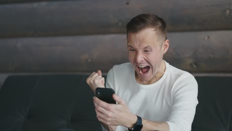 young man receives good news in message on his phone. man rejoices the news