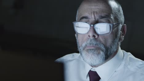 mature businessman in eyeglasses using computer