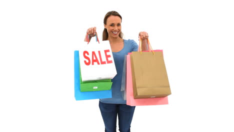 una morena sonriente sosteniendo bolsas de compras