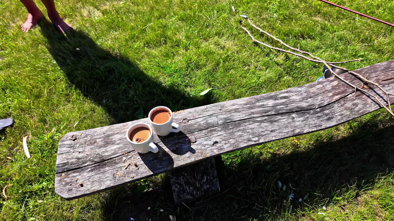 Cups filled with coffee on a wooden bench outdoor at picnic, camping