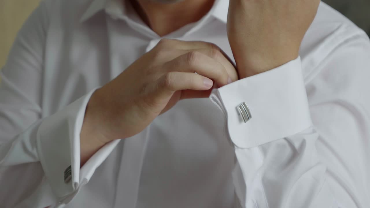 el novio ajusta los puños de la camisa y los botones de los puños. los preparativos del novio para la boda