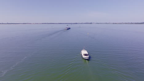 aerial footage of a classic luxemotor dutch boat navigating calm waters in the province of flevoland, the netherlands, with another vessel visible in the background under a bright blue sky