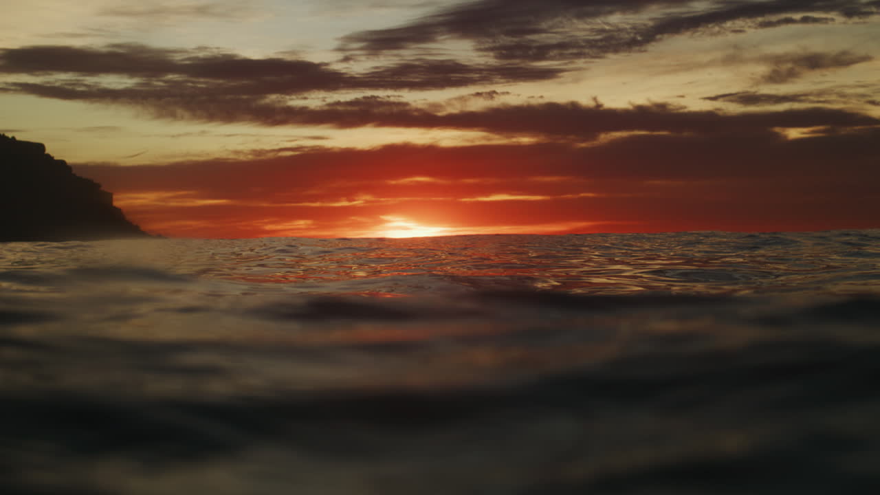 Sunset red light glow mystically spread across ocean surface, view from in water