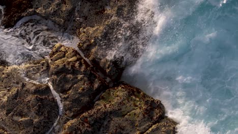 aerial view of powerful ocean waves crashing on a rocky coastline
