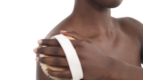 close up of black woman's upper body. girl massaging her shoulder with exfoliating wooden brush. beauty and body care concept. isolated on white background.