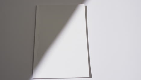 video of shadow over book with blank white pages and copy space on white background