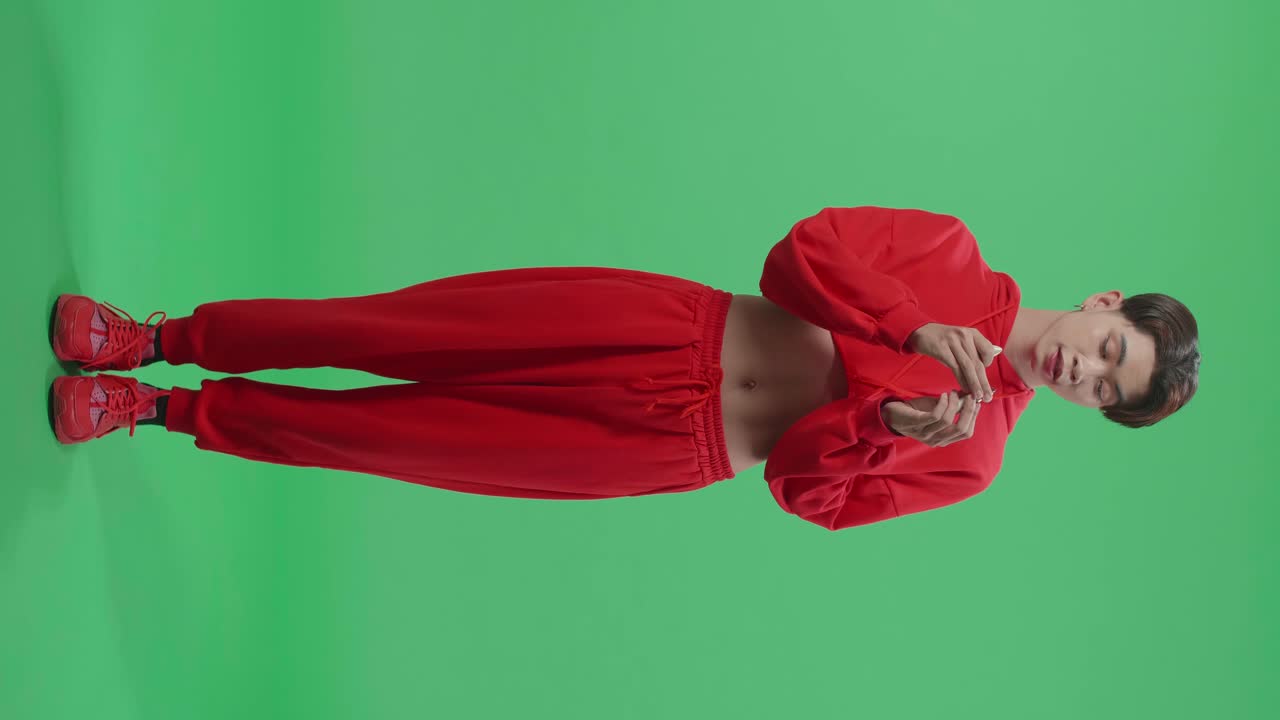 Full Body Of Asian Transgender Guy Applying Lipstick In The Green Screen Studio