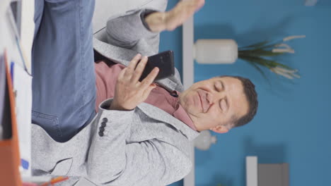 vertical video of home office worker old man getting good news on the phone.