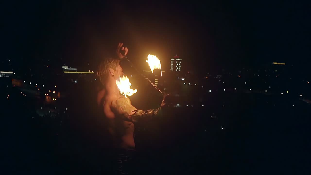 un joven hombre rubio exhala una gran corriente de fuego haciendo una bola de fuego en cámara lenta