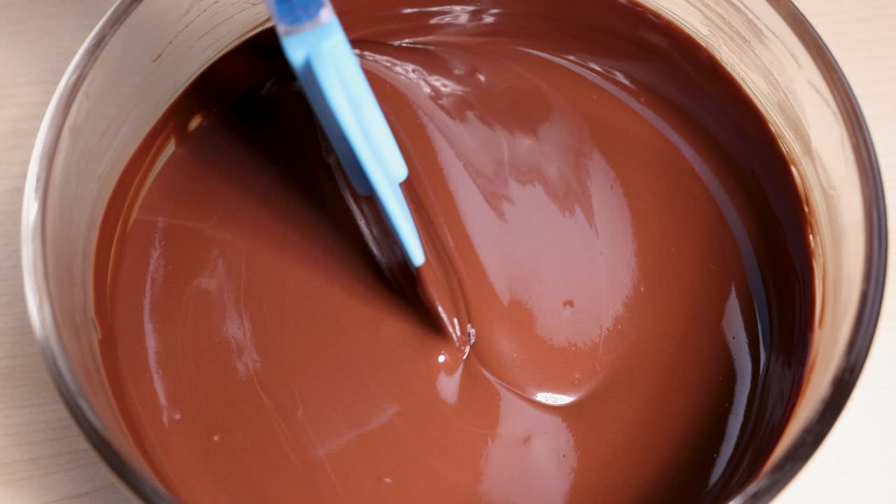 chocolate derretido suave agitado suavemente con una espátula azul en un cuenco